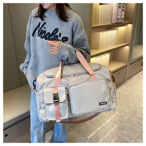 Detalle de bolsa de viaje grande con asas rosas y tejido de nailon gris resistente