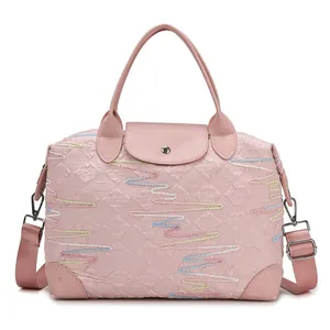 Pink large travel bag with rainbow embroidery and detachable strap shown on white background