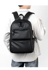 Rear view of model wearing a large black waterproof backpack with multiple compartments