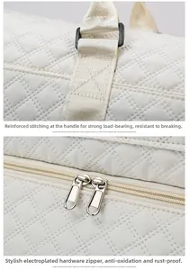 Detail of reinforced handle stitching and electroplated metal zippers on quilted travel bag