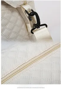 Detail view of smooth zipper and adjustable strap hook on quilted travel bag
