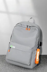 Detail view of grey nylon backpack featuring orange zippers and external USB charging port