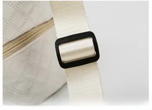 Detail showing adjustable shoulder strap with plastic buckle on quilted travel bag