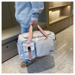 Detalle de bolsa de viaje gris con correas rosas mostrando bolsillos y tela impermeable