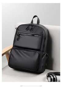 Detail of a black waterproof business backpack with dual front zippers on a grey sofa