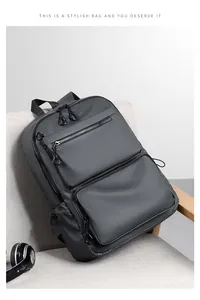 Detailed view of the dark grey waterproof backpack with multi-layer zippers on a chair