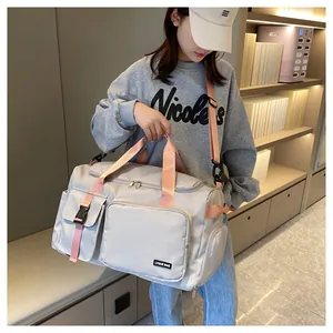 Detalle de la bolsa de viaje gris claro con correas rosas y bolsillos con cremallera