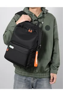 Detail of black commuter backpack with orange zipper tags and external USB port