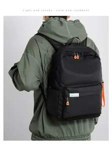Detail of black waterproof nylon backpack featuring orange zipper pulls and grey reflective strip