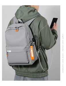 Gray backpack featuring external USB charging port and orange fashion ribbon details