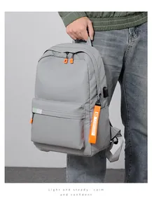 Detail view of large grey backpack featuring an external USB port and orange zipper tags