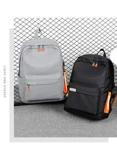 Detail of grey and black nylon backpacks featuring USB port and orange zipper pulls