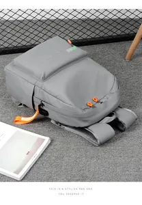 Detail of grey backpack featuring orange zipper pulls and branded fashion straps