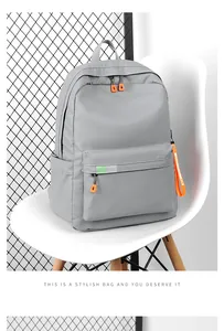 Detailed view of grey waterproof backpack with orange zippers on a modern white chair