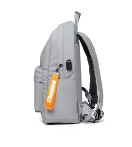 Side view of gray backpack featuring a built-in USB port and orange lettered zipper pull
