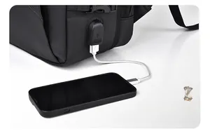 Close-up of black waterproof travel backpack with integrated USB charging port and cable