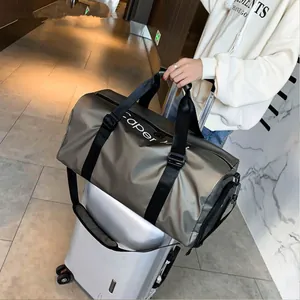 Borsone sportivo impermeabile champagne con cinghie nere su valigia argentata