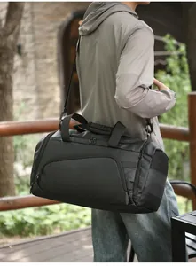 Detail of a large black waterproof fitness bag with reinforced handles and side mesh pocket