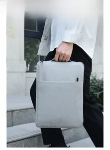 Light gray laptop sleeve with top handle and front pocket shown in outdoor use