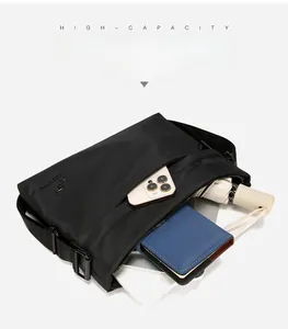 Detail showing the large capacity of a black oxford crossbody bag holding a tablet and umbrella