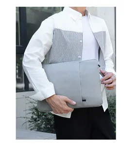 Grey laptop sleeve with retractable handle and front pocket shown in outdoor use
