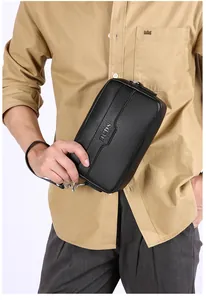 Detail einer schwarzen Clutch aus genarbtem Leder mit HCDS-Metalllogo und Handschlaufe