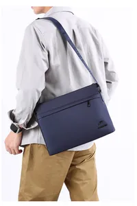 Detail of navy blue men messenger bag showing the brand embossed leather shoulder strap