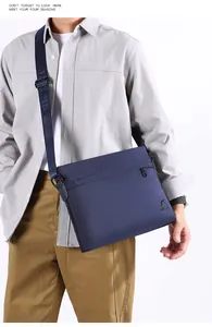 Detail of navy blue oxford crossbody bag with adjustable strap and metal logo