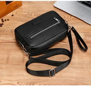 Detail van zwarte crossbodytas van generfd leer met afneembare riem op houten bureau