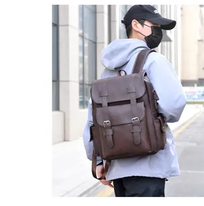 Close-up of brown vintage leather backpack with dual buckle straps and matte texture