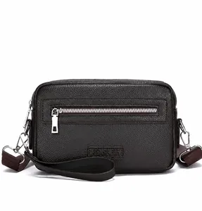 Detail van de bruine crossbodytas van generfd leer met rits aan de voorkant en logo