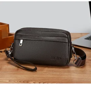 Dettaglio borsa a tracolla in pelle marrone con tre tasche a zip e logo HCDS goffrato