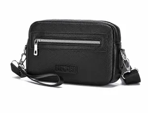 Detailopname van zwarte crossbodytas van generfd leer met zilveren rits en gegraveerd logo