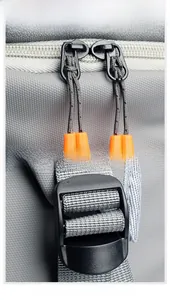 Detail of waterproof grey fabric with orange dual zippers and adjustable strap buckles