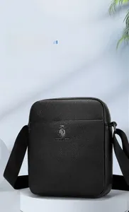 Close-up of a black litchi grain leather shoulder bag with metallic logo on a pedestal