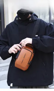 Brown leather sling bag detail with anti-theft security lock and integrated USB port