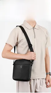 Detail of men's black crossbody bag with lychee grain texture and embossed strap