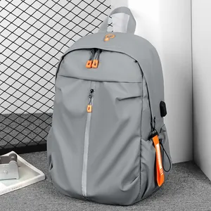 Grey waterproof backpack with orange accents and external USB port for travel and school