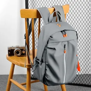 Waterproof grey nylon backpack with orange zipper details hanging on a chair