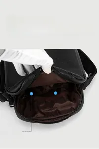 Close-up of the black leather crossbody bag interior showing spacious main pocket and zipped pocket
