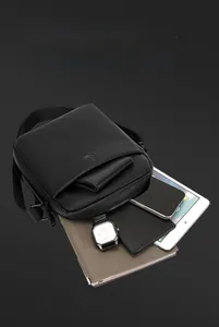 Detail view of large capacity black leather crossbody bag interior holding multiple items