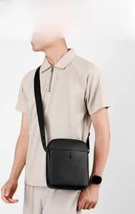 Detail of black lychee grain leather crossbody bag showing logo on wide shoulder strap