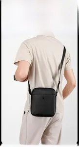 Detail of black textured leather shoulder bag with adjustable strap and metal zipper