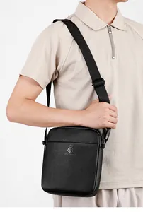 Detail of black lychee grain leather crossbody bag with adjustable wide strap and logo
