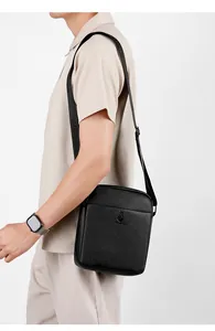 Model wearing a black leather crossbody bag with adjustable strap and textured finish