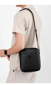 Detail of black pebbled leather crossbody bag with embossed logo and adjustable strap