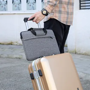 Gray laptop bag featuring a back strap secured to a suitcase handle for easy travel