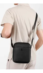 Detail view of black lychee leather crossbody bag with logo and adjustable strap