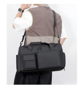 Modello maschile che porta un grande borsone nero impermeabile con tasche multiple e tracolla
