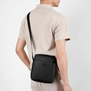 Business casual black leather messenger bag for men shown on a model in a side view